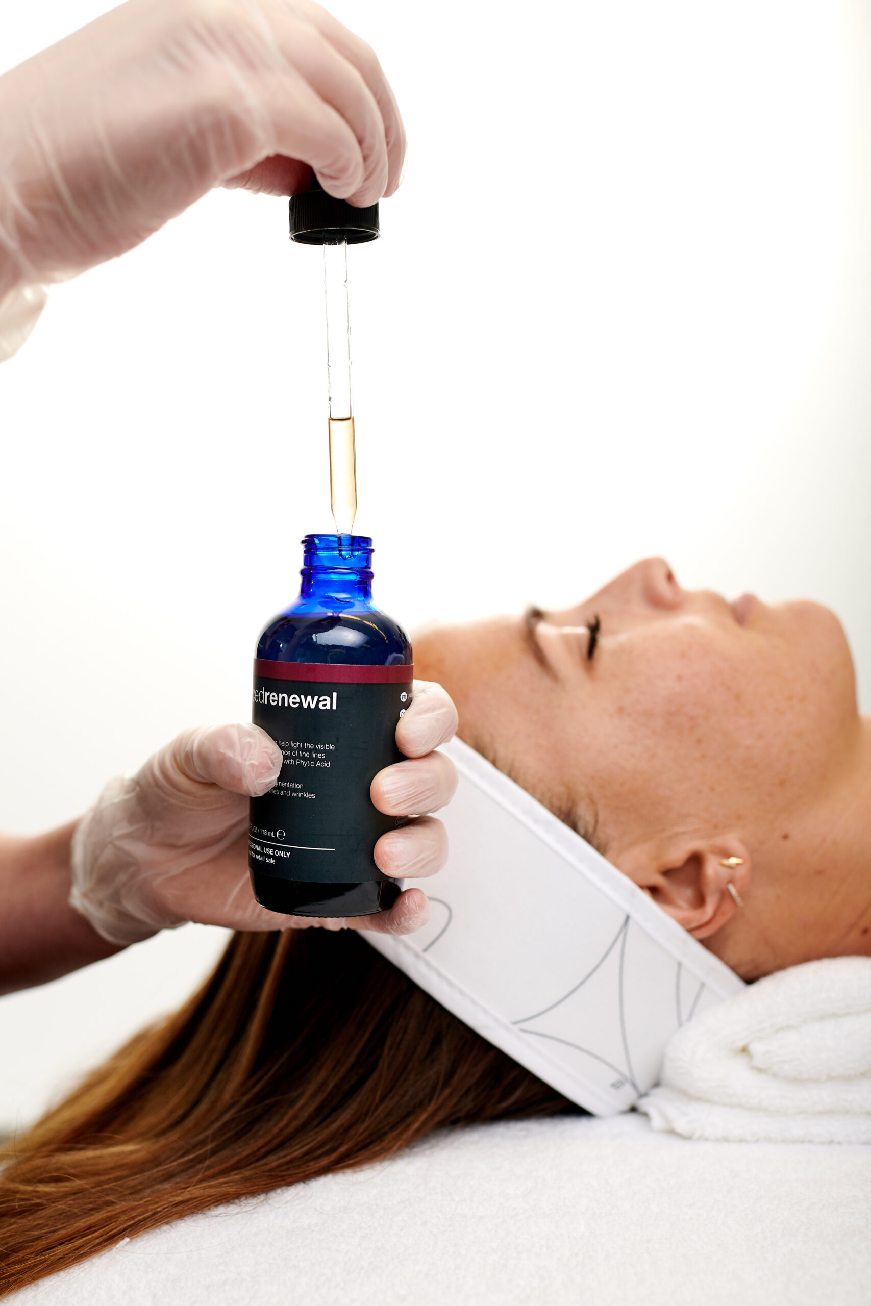 Professionelle Gesichtsbehandlung mit Dermalogica Pro Power Peel - Pipette mit Serum über einer liegenden Frau